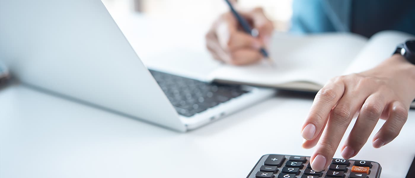 Close up of a fleet consultant using a calculator and laptop to ensure her customer's fleet vehicles are registered. Close up of a fleet consultant using a calculator and laptop to ensure her customer's fleet vehicles are registered.