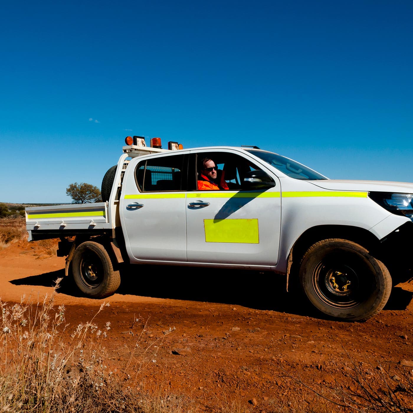A small business owner driving a ute on a red dirt road in Australia. A small business owner driving a ute on a red dirt road in Australia.