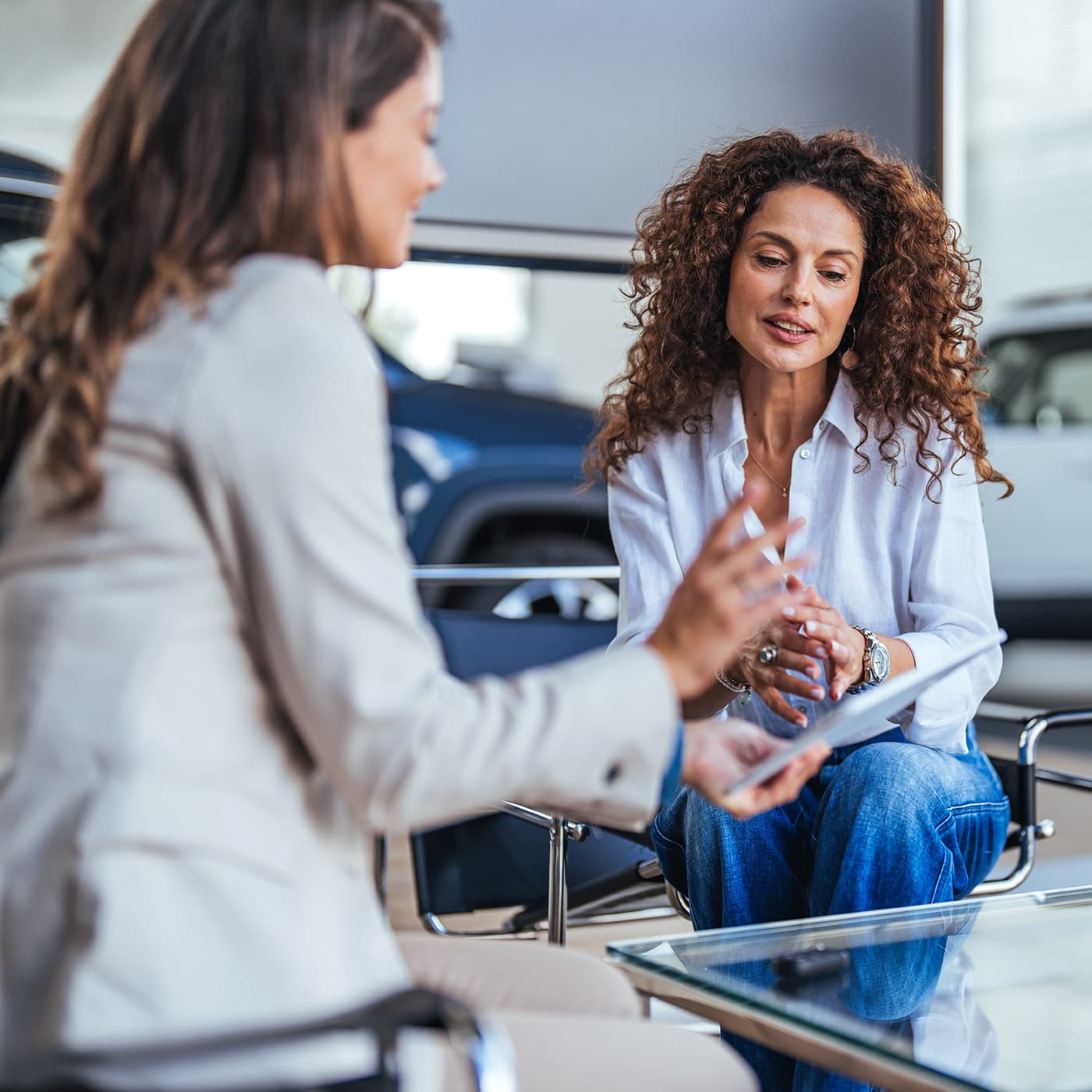 Smiling car saleswoman discussing a contract with a female customer. Smiling car saleswoman discussing a contract with a female customer.