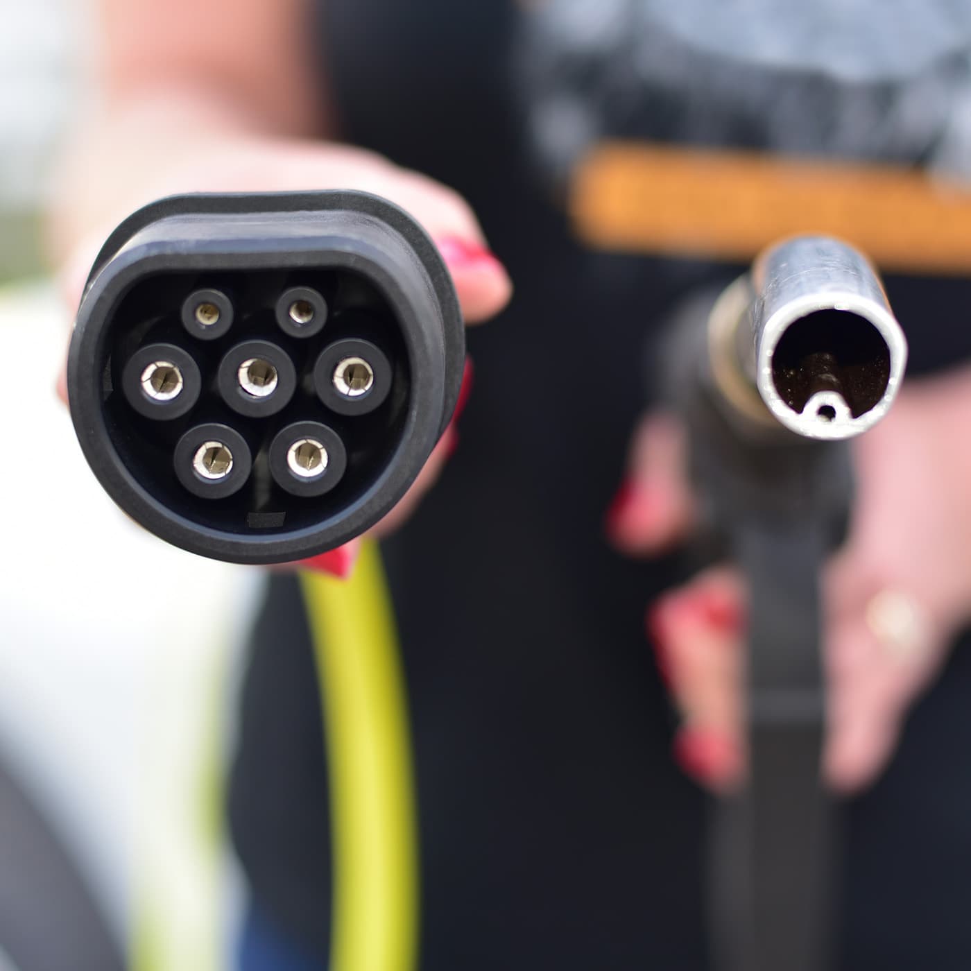 Fuel nozzle and electric car charger plug. EV vs petrol. Fuel nozzle and electric car charger plug. EV vs petrol.