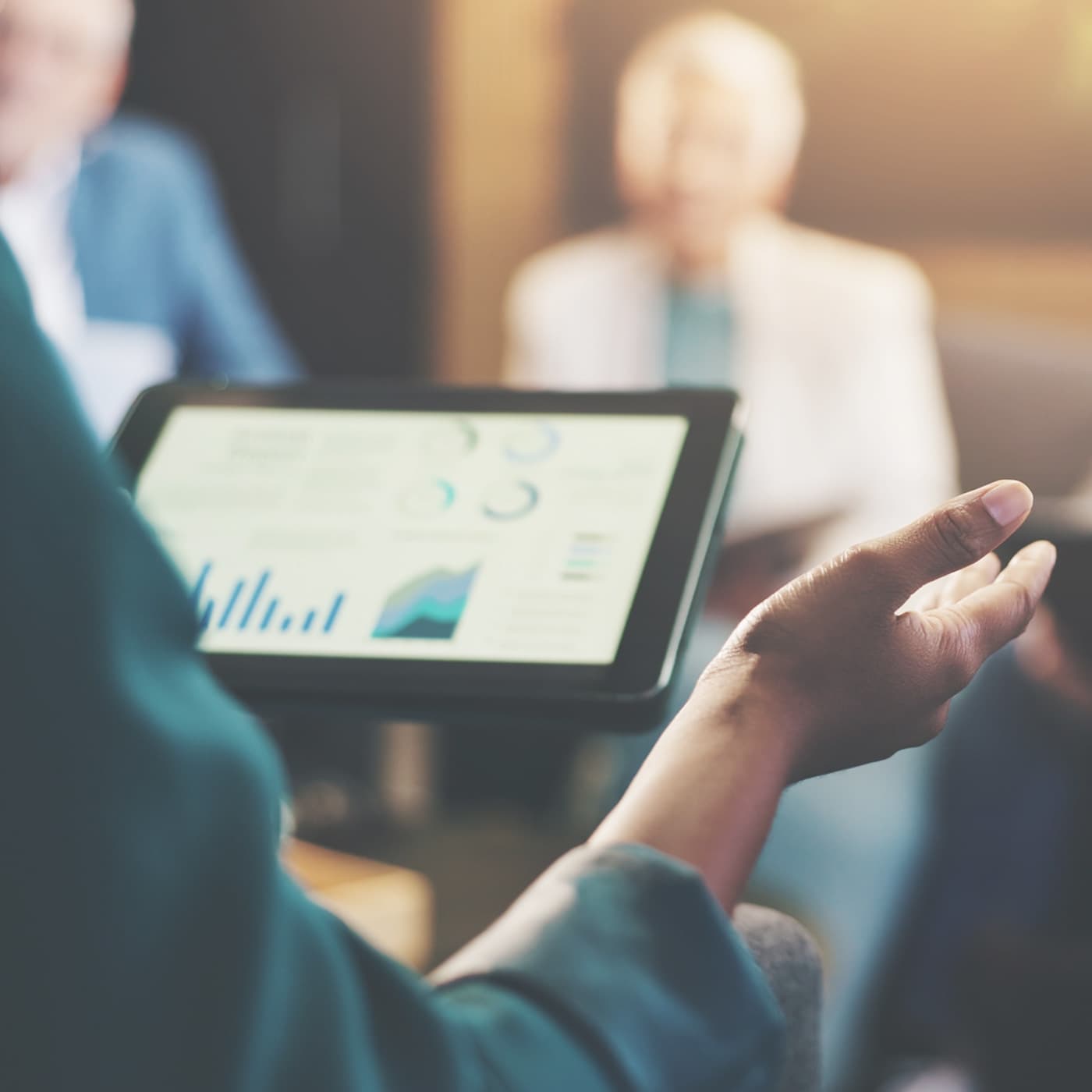 Reporting data displayed on a tablet being discussed in a team meeting. Reporting data displayed on a tablet being discussed in a team meeting.