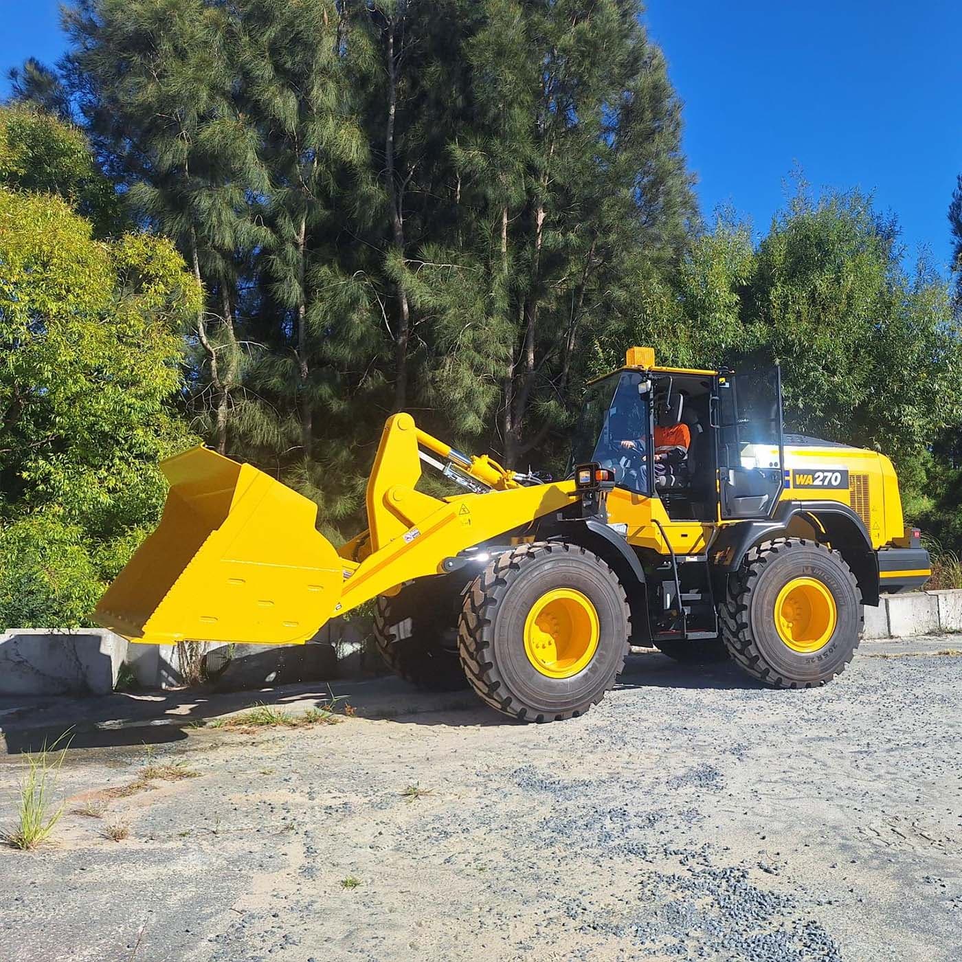 Side view of a yellow tractor in action surrounded by trees. Side view of a yellow tractor in action surrounded by trees.