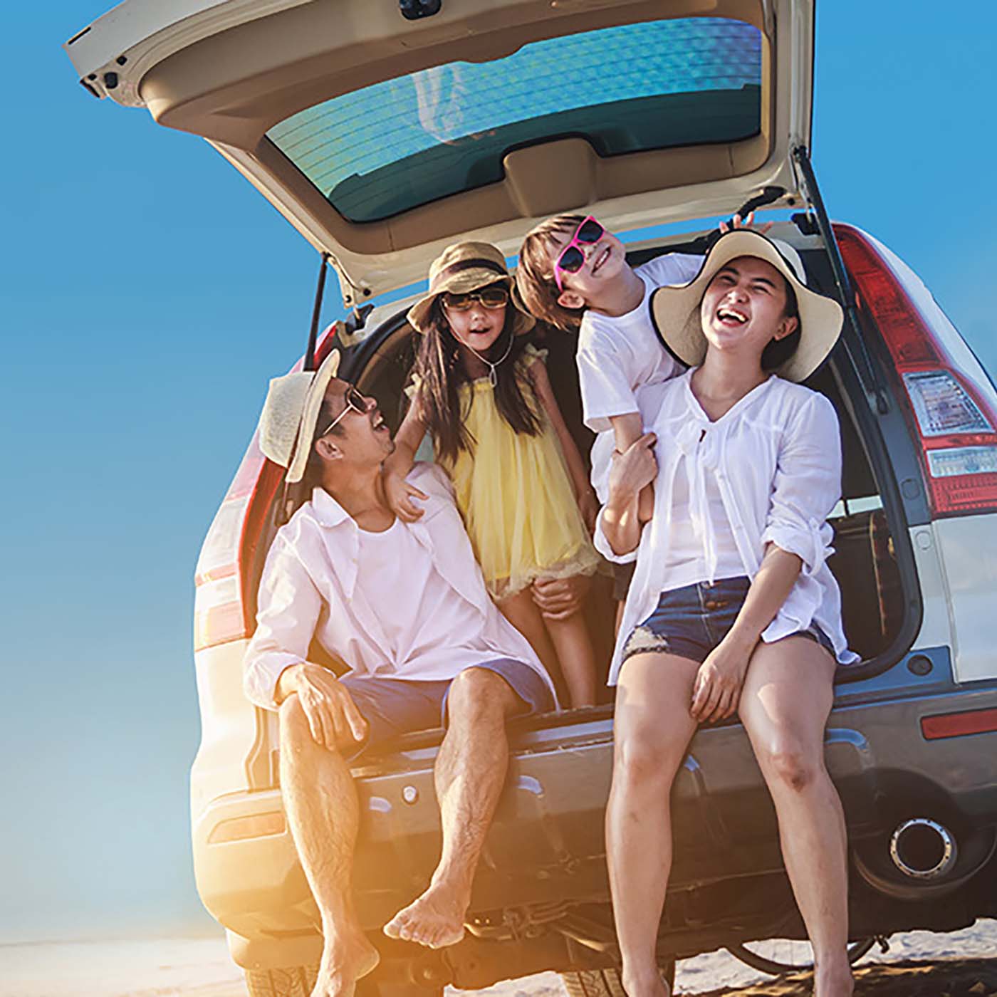 A family sitting at the back of their SUV at the beach, laughing and enjoying themselves. A family sitting at the back of their SUV at the beach, laughing and enjoying themselves.
