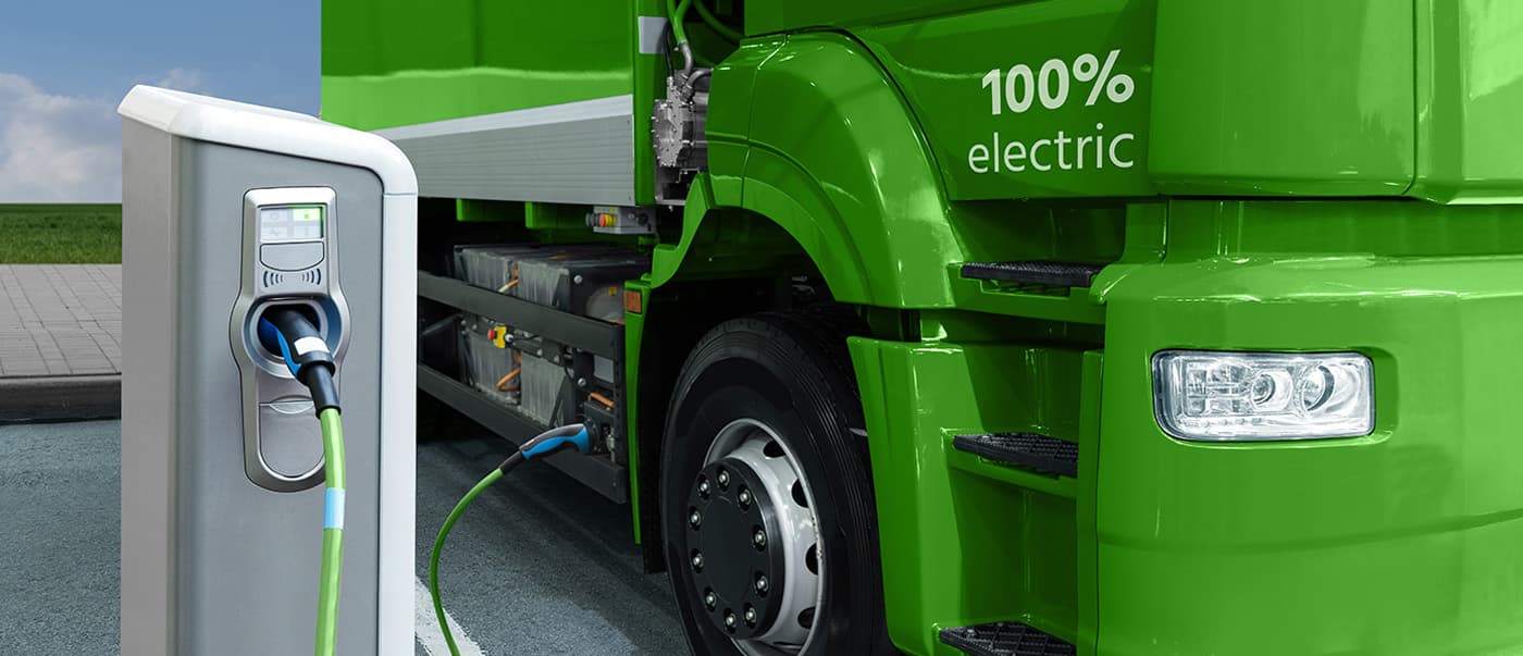 Green EV truck is being charge at an EV charging station. Green EV truck is being charge at an EV charging station.