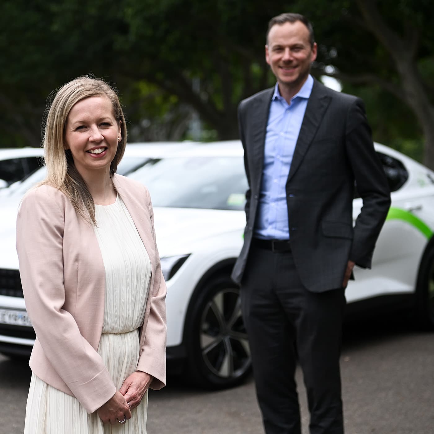 Lauren Lister and Christopher Tulloch from Custom Fleet standing in front of three white Custom Fleet branded EV with green markings. Lauren Lister and Christopher Tulloch from Custom Fleet standing in front of three white Custom Fleet branded EV with green markings.