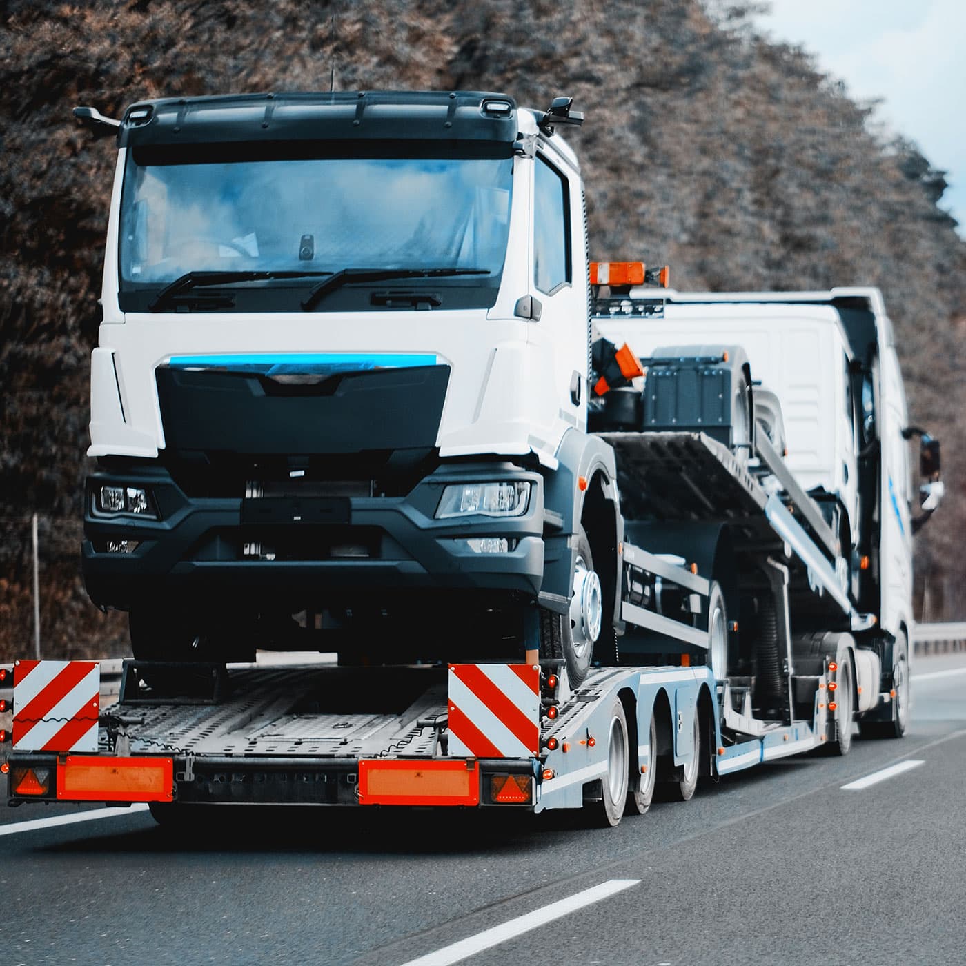 Towing truck with a brand-new commercial vehicle being transported to another location. Towing truck with a brand-new commercial vehicle being transported to another location.