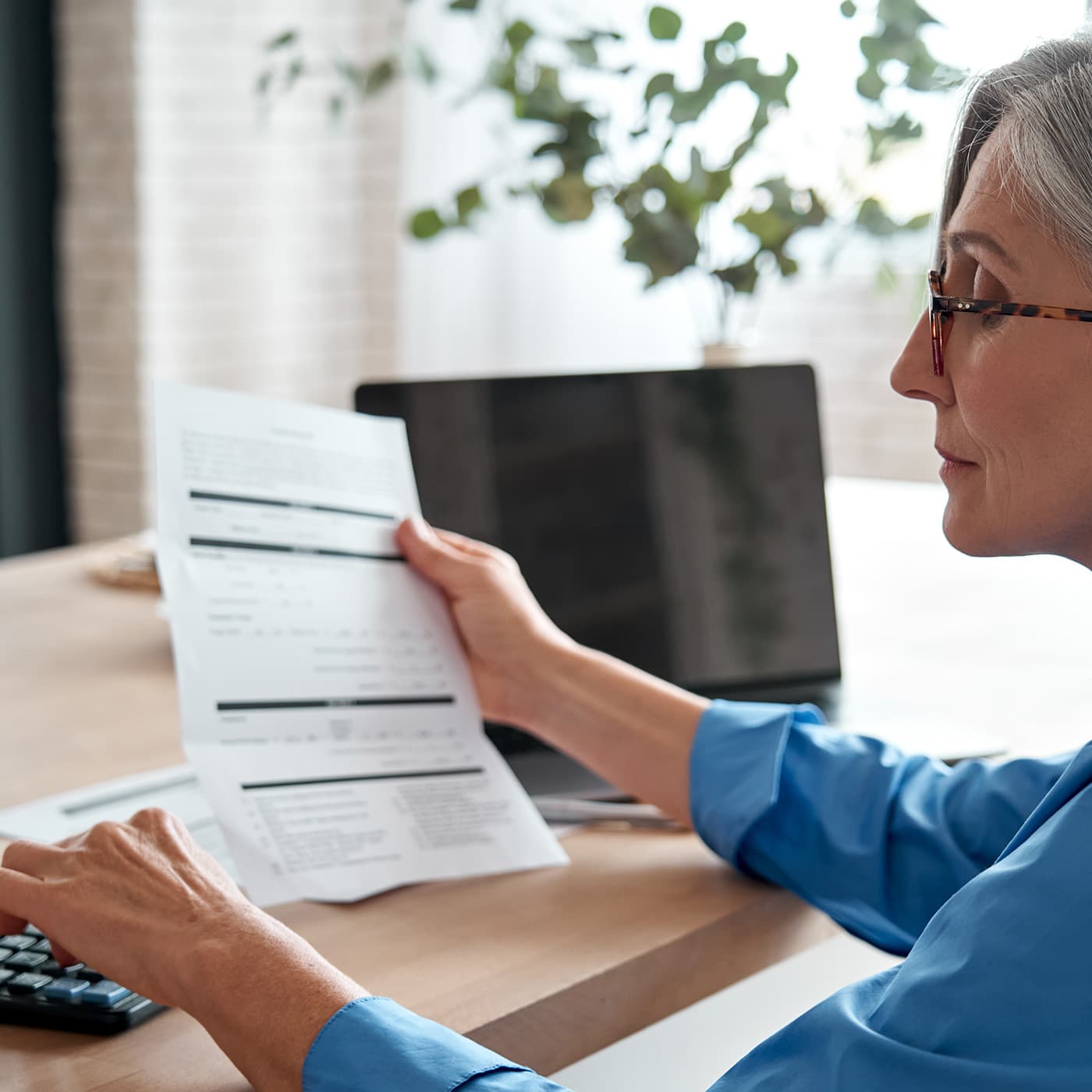 Senior mature business woman holding paper bill using calculator. Senior mature business woman holding paper bill using calculator.