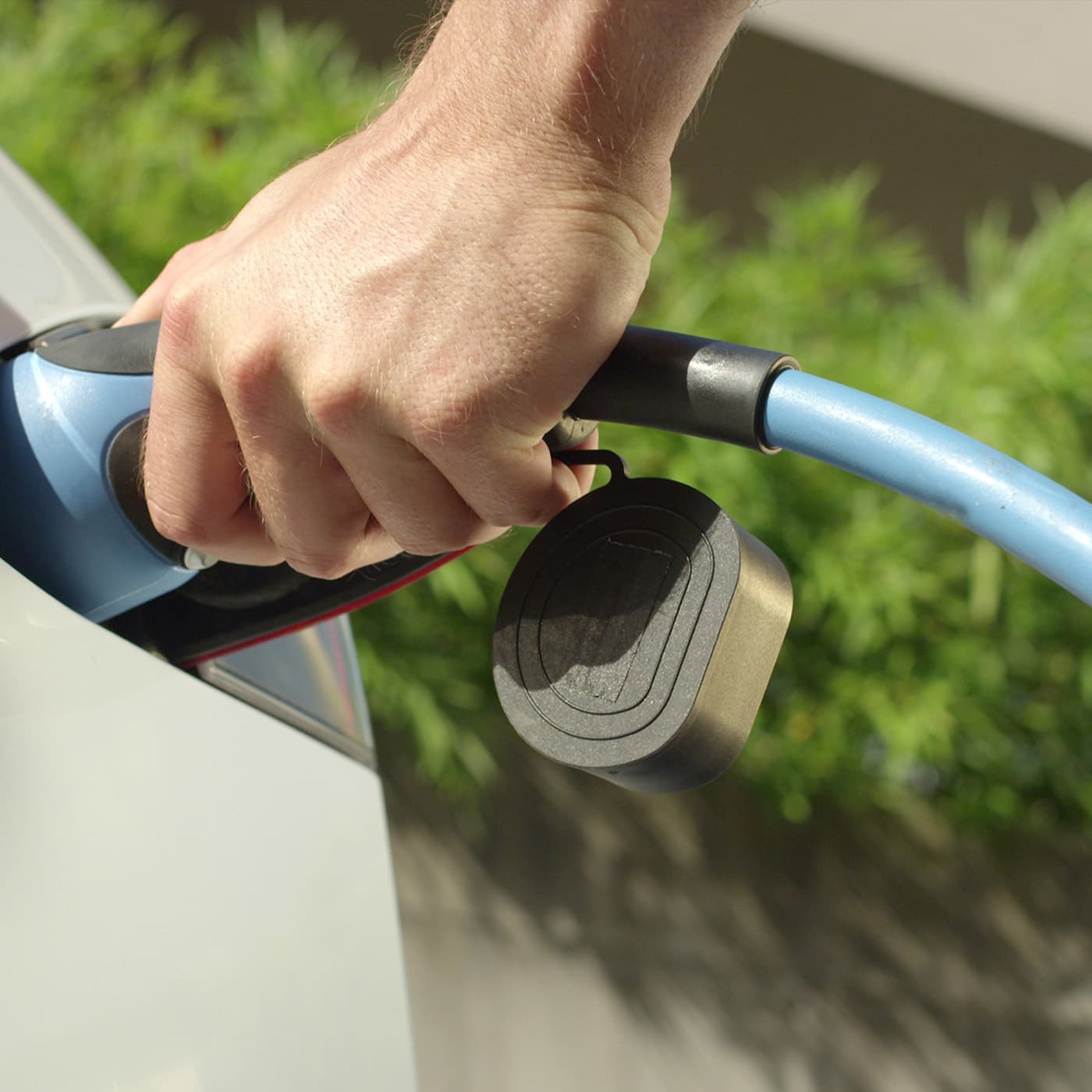 Close up of a man plugging in electric car to a charging station. Close up of a man plugging in electric car to a charging station.