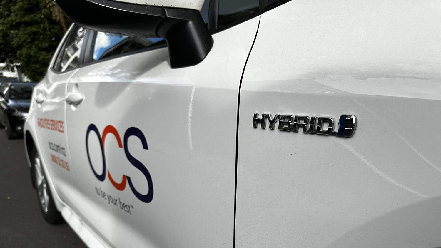 The hero image shows a close up of the side of a white hybrid PHEV vehicle, with the OCS be your best logo.