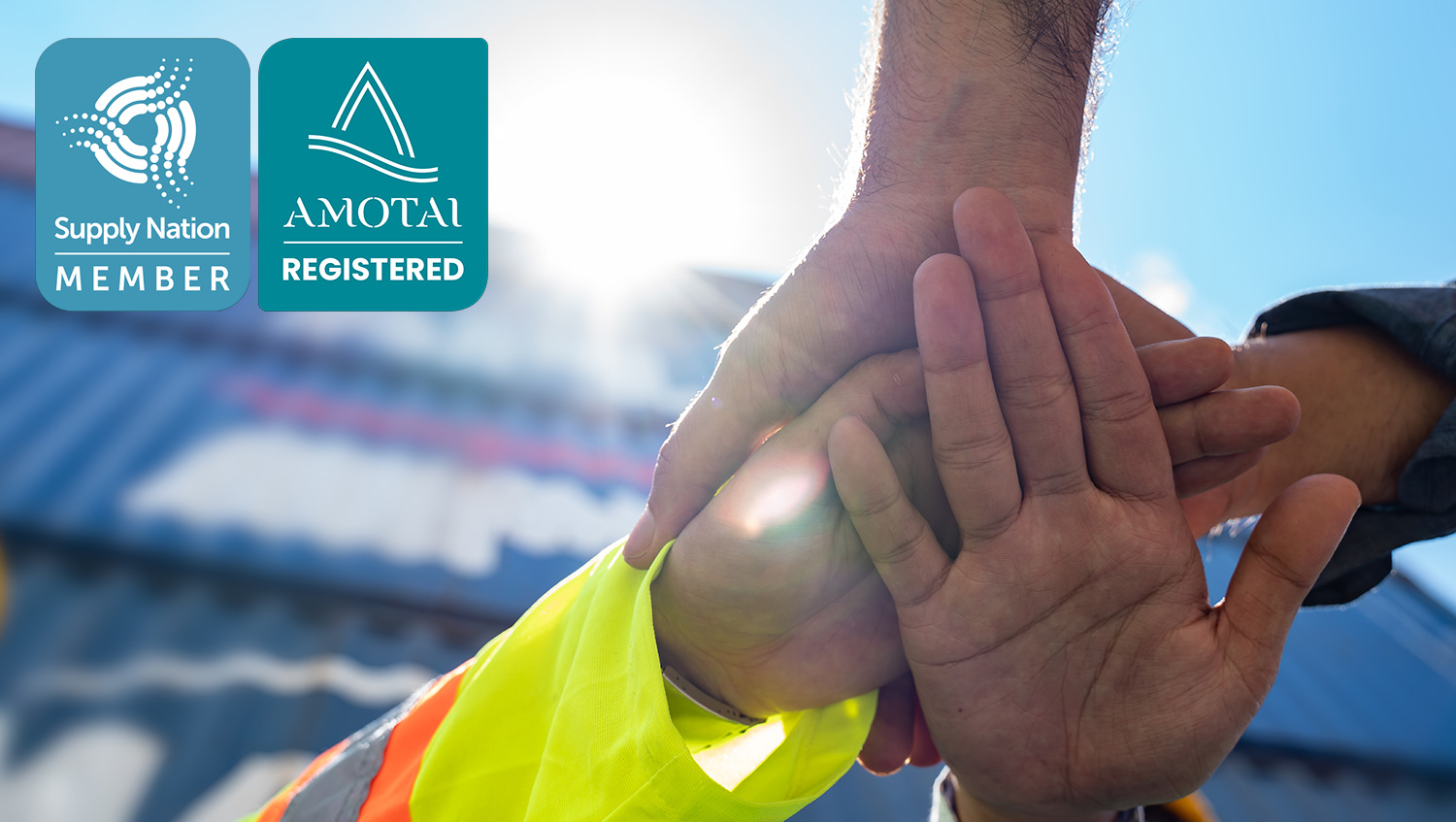 Close up view of a team of people with their hands stacked on top of each other together at a container yard.
